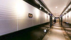 A modern hotel corridor with a reflective floor, recessed lighting, and a framed picture on the wall. - Cheonan E (Cheonan)