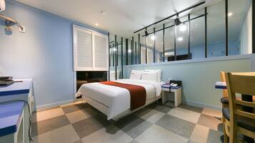 A hotel room with a bed, a desk, a chair, and a large mirror.