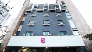 A modern building with a prominent 'e' logo on the ground floor, multiple balconies, and a brick facade. - Cheonan E (Cheonan)