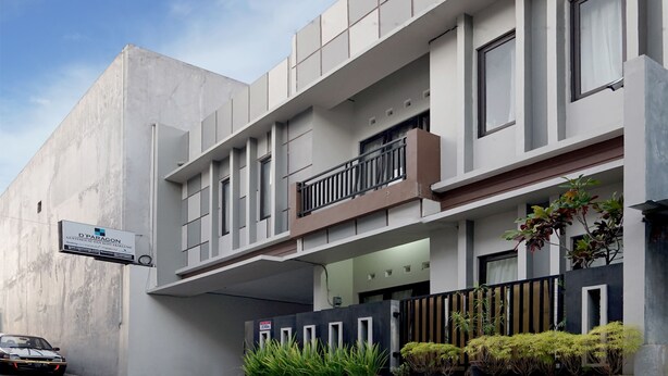A modern building with a sign for D'Paragon Guesthouse. It features a balcony with a railing, a gated entrance, and potted plants. - Dparagon Pamela 1 (Depok)