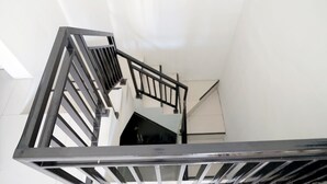 A modern staircase with a metal handrail and a white wall in the background. - Dparagon Pamela 1 (Depok)