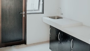 A kitchen with a white countertop, a stainless steel sink, and black cabinets. - Dparagon Pamela 1 (Depok)