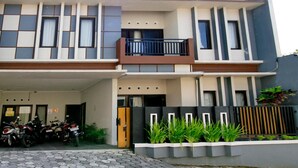 A modern two-story house with a balcony, a garage with motorcycles, and a gated entrance. - Dparagon Pamela 1 (Depok)