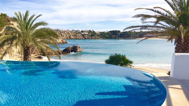 Ein klares, blaues Schwimmbecken mit Blick auf das Meer und die felsige Küste.