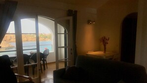 Ein Wohnzimmer mit einer Couch, einem Esstisch mit Stühlen und Meerblick durch eine offene Tür.
