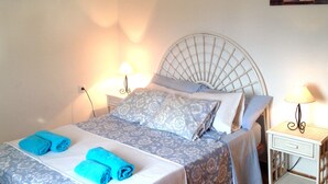 Ein ordentlich bezogenes Bett mit blauen Handtüchern, einem weißen Kopfteil und zwei Nachttischlampen.
