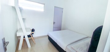 Una habitación pequeña y poco amoblada con una cama, un escritorio y una silla.