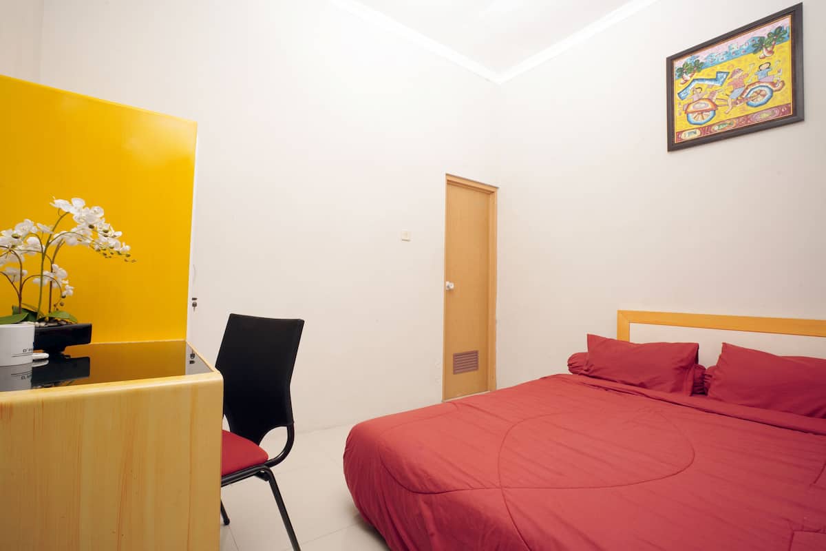 A room with a bed, a desk, a chair, and a door.