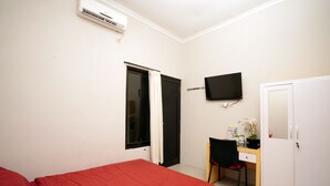 Un dormitorio con cama, escritorio, silla, televisor y armario.