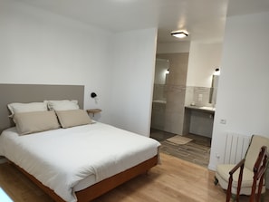A bedroom with a bed, bedside table, and a chair. - Grande Propriété le Long du Ruisseau (ST NOLFF)