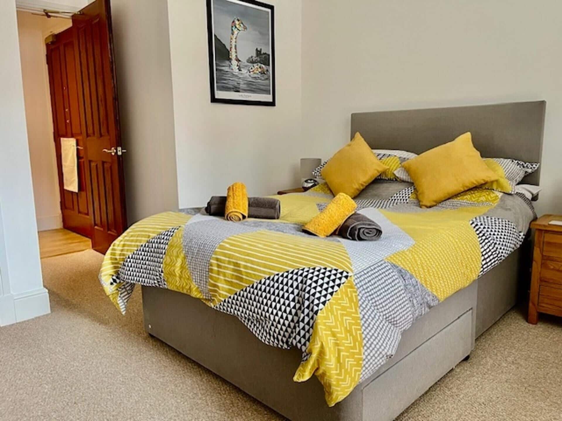 A bedroom with a bed, pillows, and a blanket.