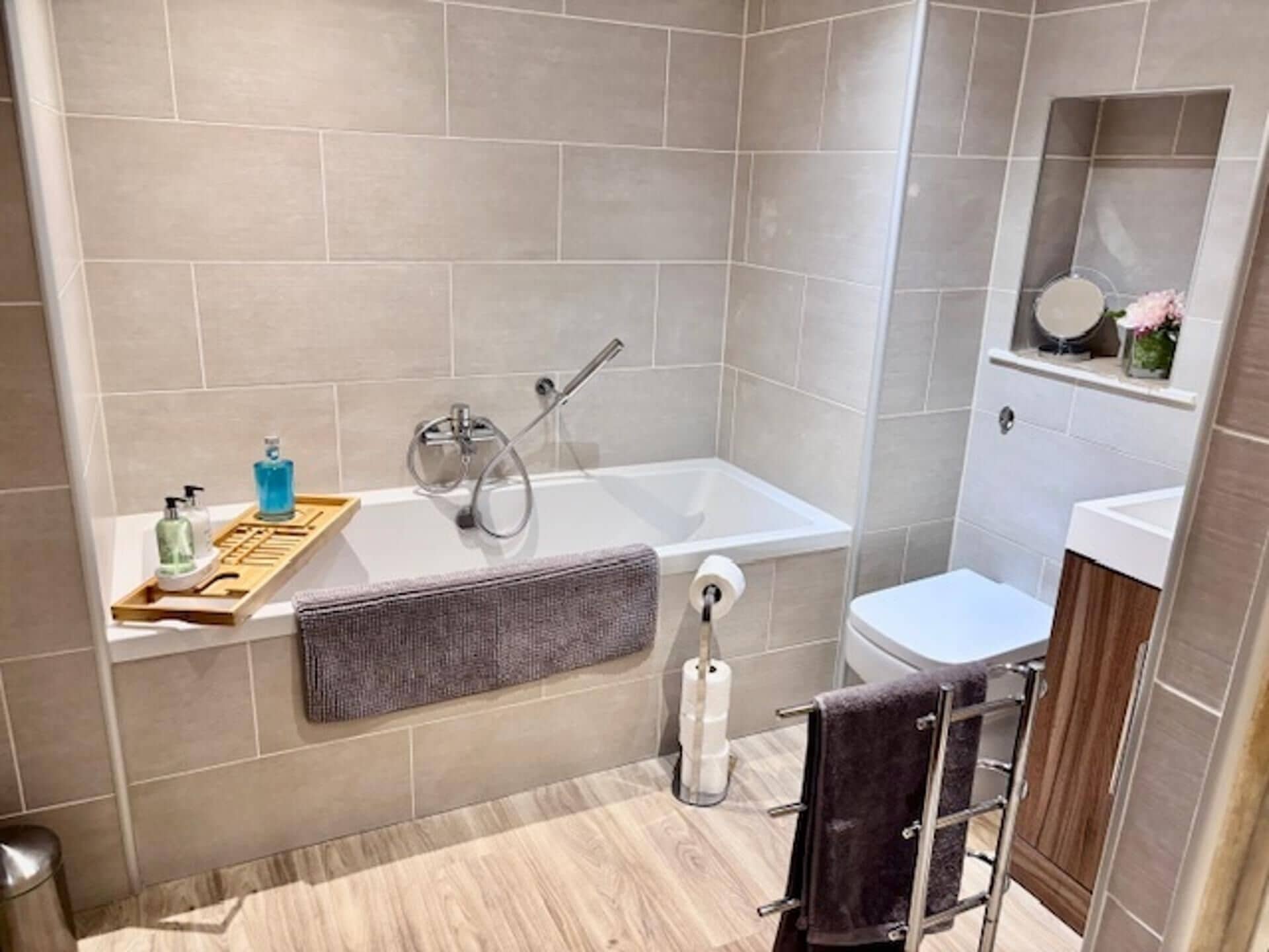 A modern bathroom with a bathtub, toilet, and a vanity with a mirror.
