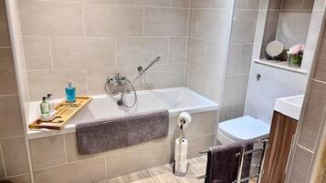 A modern bathroom with a bathtub, toilet, and a vanity with a mirror.