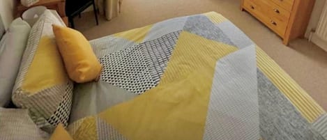 A bedroom with a bed, a dresser, a window with curtains, and a chair.