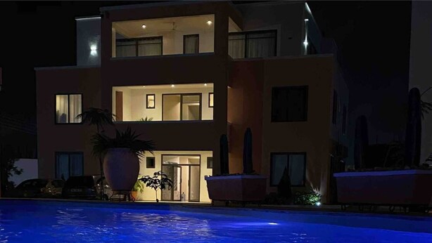 A modern two-story house with a swimming pool in front.
