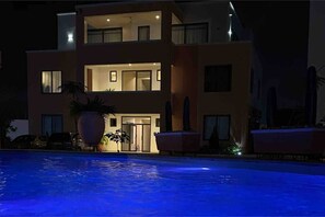 A modern two-story house with a swimming pool in front.