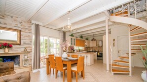 Amplia sala de estar con mesa de comedor, sillas, chimenea y una escalera que sube a un nivel superior.