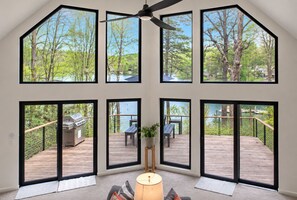 Una habitación con ventanas amplias que ofrecen vistas a una terraza y árboles.