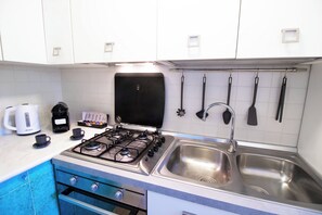 A kitchen with a gas stove, two sinks, a coffee maker, and a kettle. - La Scalinatella - Private apartment with Sea View (Forio)