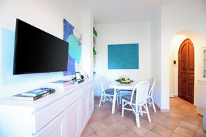 Una cucina moderna con una TV a schermo piatto, un tavolo da pranzo con sedie e una parete decorata in blu.