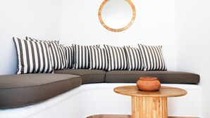 A modern living room with a sectional sofa, a round wooden coffee table, and a round mirror on the wall. - ROOFTOP TITINA: exclusive sea view apartment (Forio)