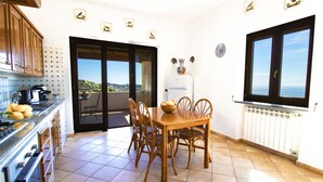 A kitchen with a dining table and chairs, a view through the door, and a window with a view. - ROOFTOP TITINA: exclusive sea view apartment (Forio)
