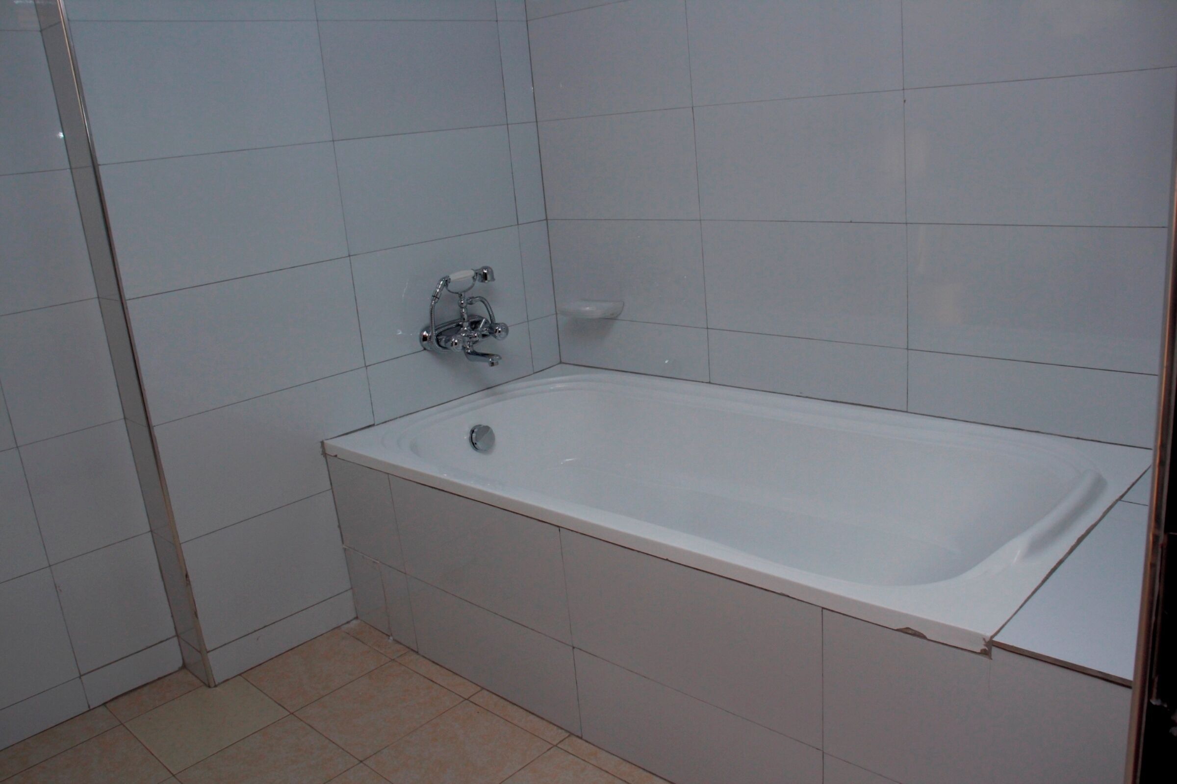 Un baño con una bañera blanca, paredes y suelo de azulejos.