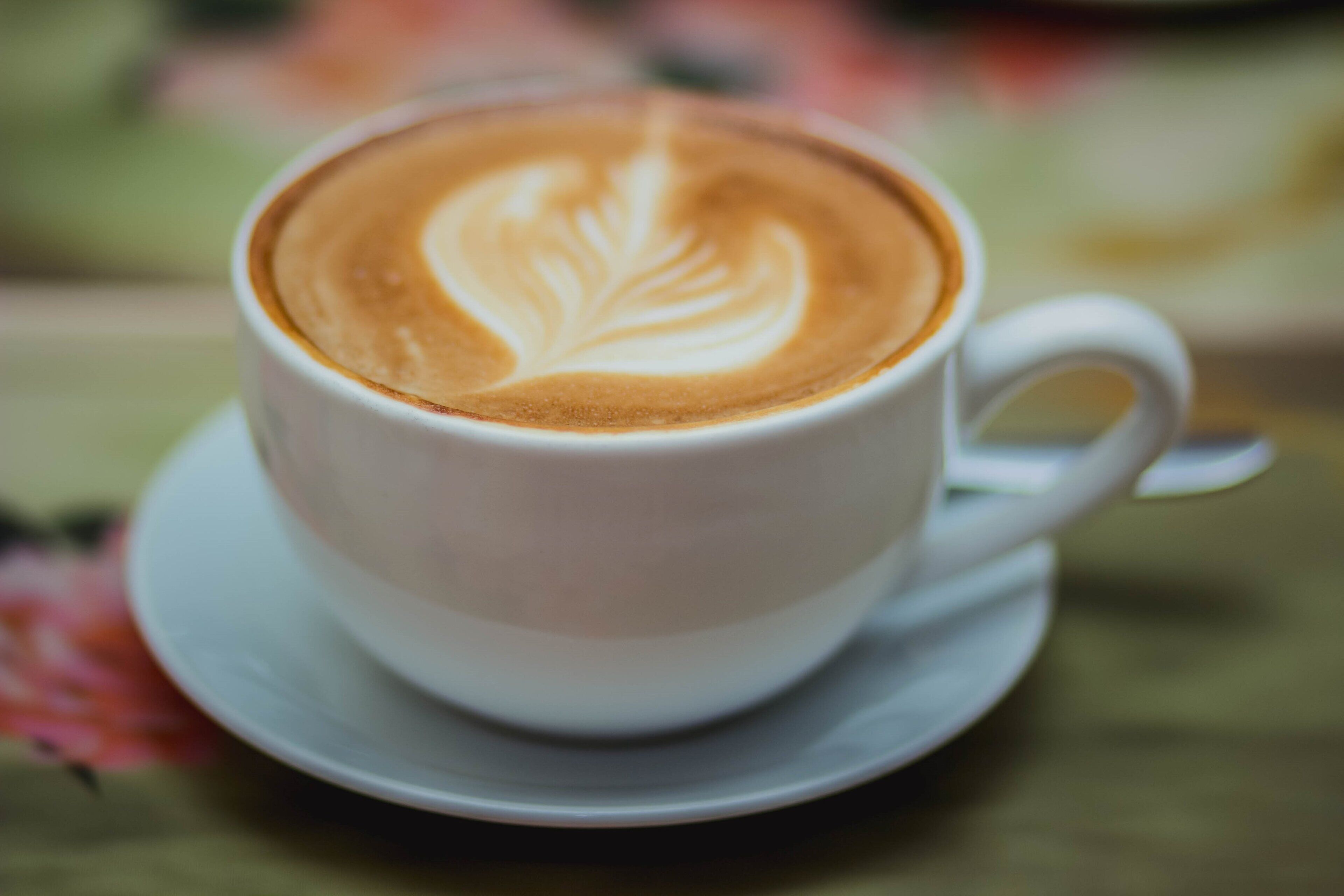 A cup of coffee with a leaf design on the foam.