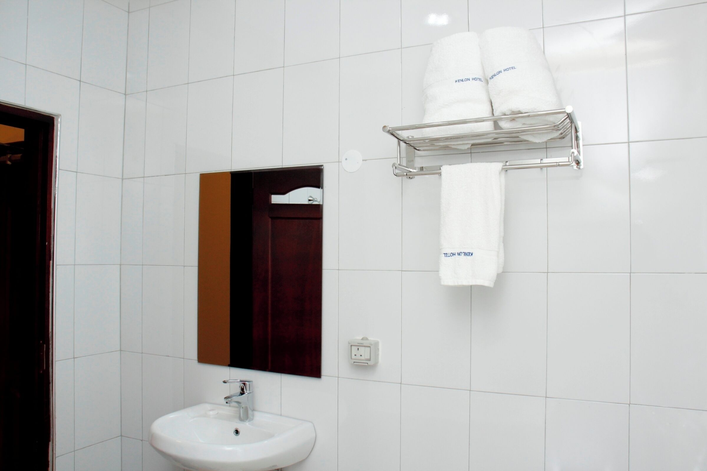 Une salle de bain avec un lavabo blanc, un miroir et un porte-serviettes avec deux serviettes.