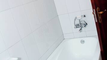Ein Badezimmer mit einer weißen Badewanne, einer Duschbrause und einer Toilette.