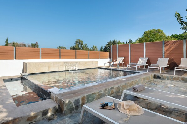 Une piscine avec des chaises longues et une terrasse en pierre.