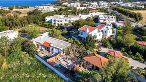 Ett bostadsområde med hus, en swimmingpool och utsikt över havet.