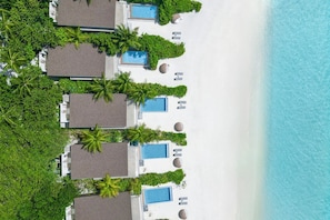 Un complexe hôtelier doté de plusieurs bungalows sur pilotis, chacun disposant d’une piscine privée et étant entouré d’une végétation luxuriante.