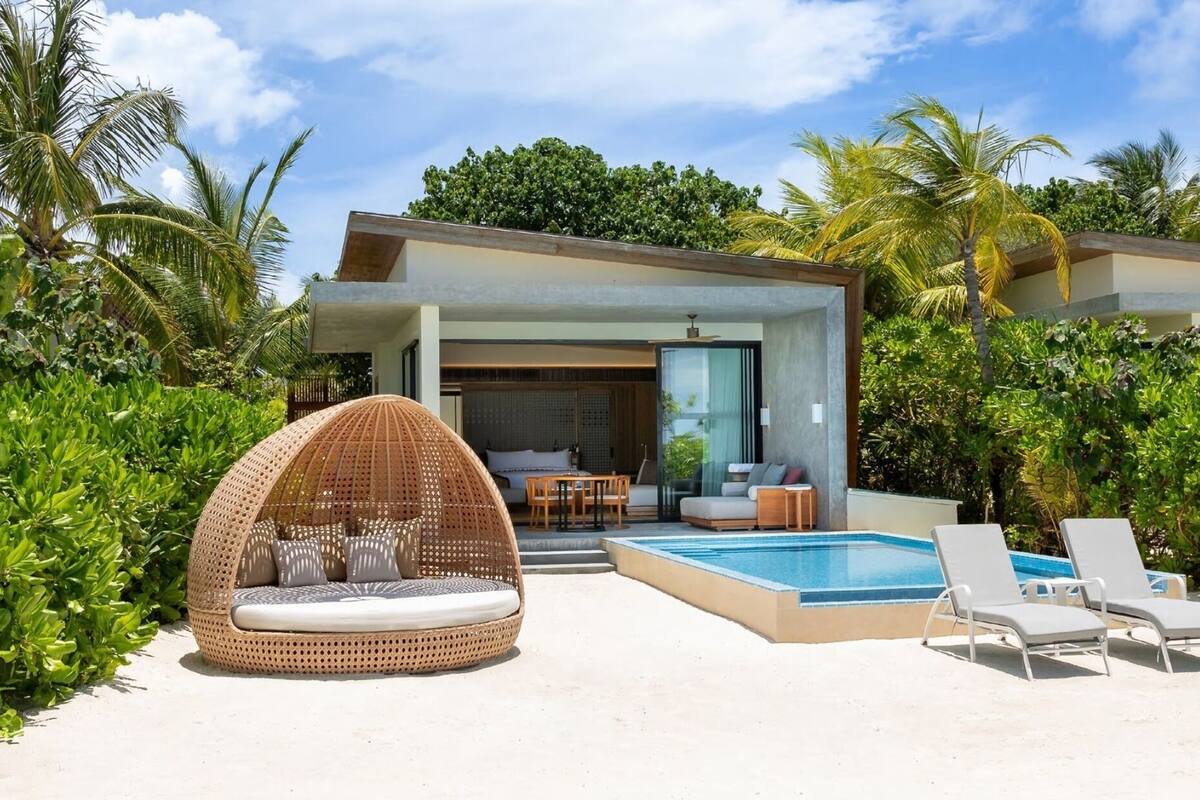 A modern villa with a pool, outdoor seating, and lush tropical vegetation.