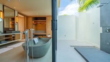 Un baño moderno con una bañera grande, una ducha a pie y un área de ducha con mampara de vidrio.