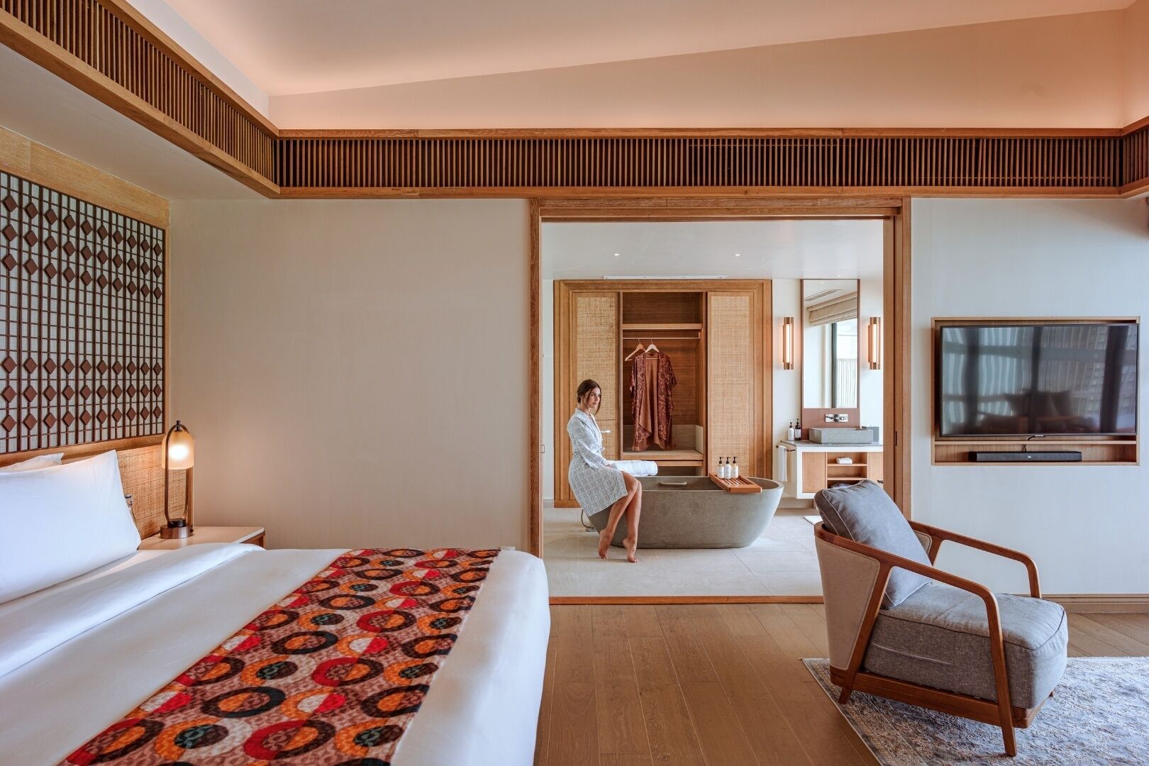 A hotel room with a bed, a chair, a bathtub, and a walk-in closet.