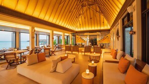 A spacious lounge area with a high ceiling, large windows offering a view of the sea, and a bar area in the background. - Kuda Villingili Maldives, Free Return Transfers 03 nights & above (Kuda Villingili)