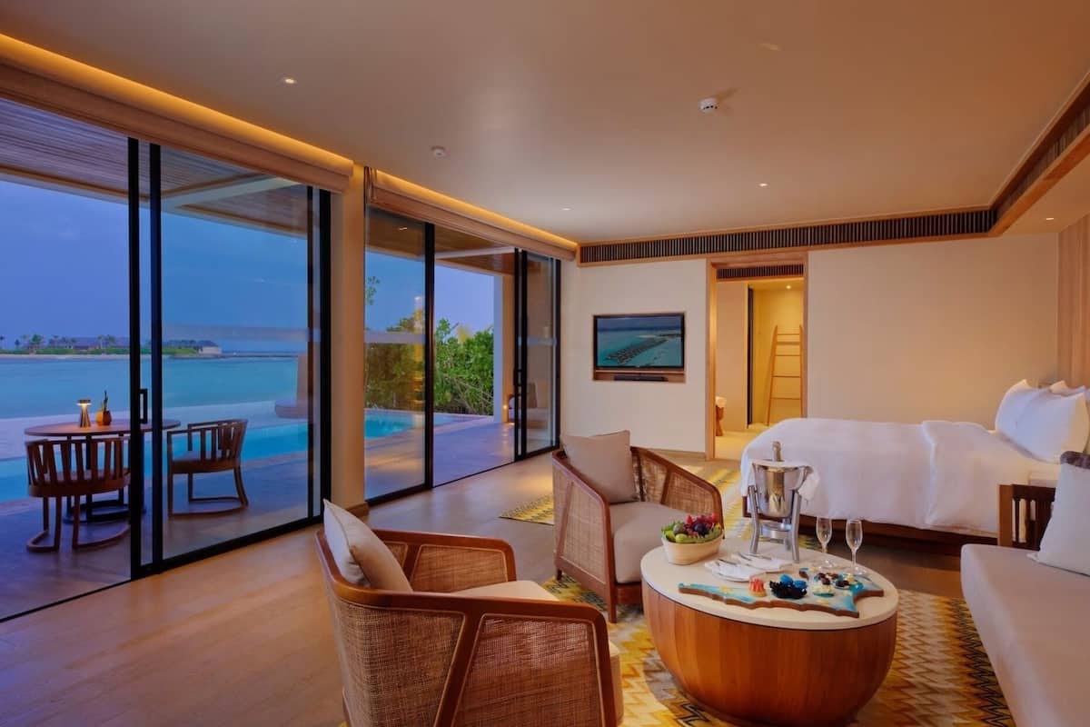 A modern hotel room with a large balcony, a pool, and a view of the ocean.