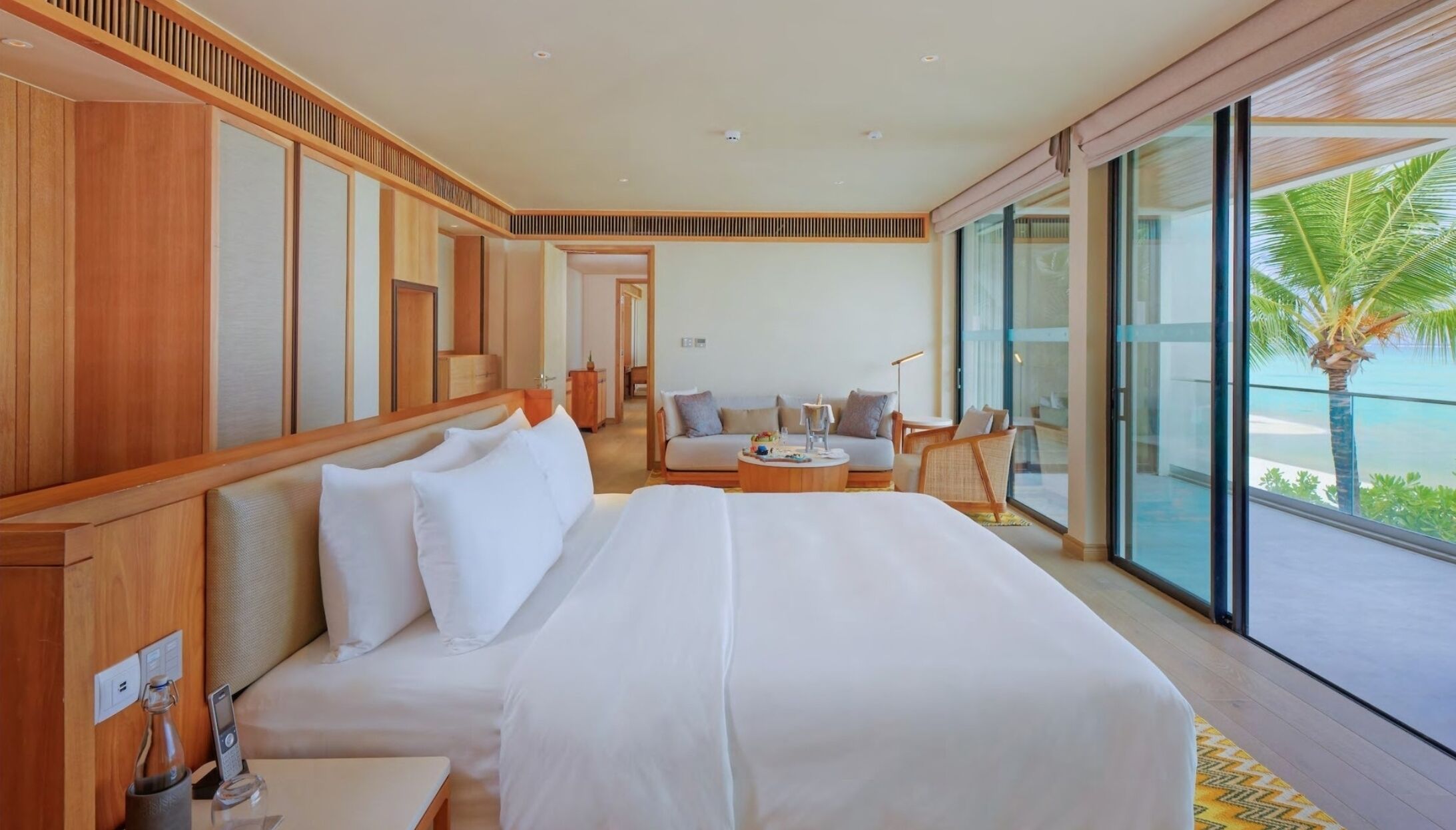 Une chambre d’hôtel avec un grand lit, un canapé, une table basse et une vue sur l’océan.