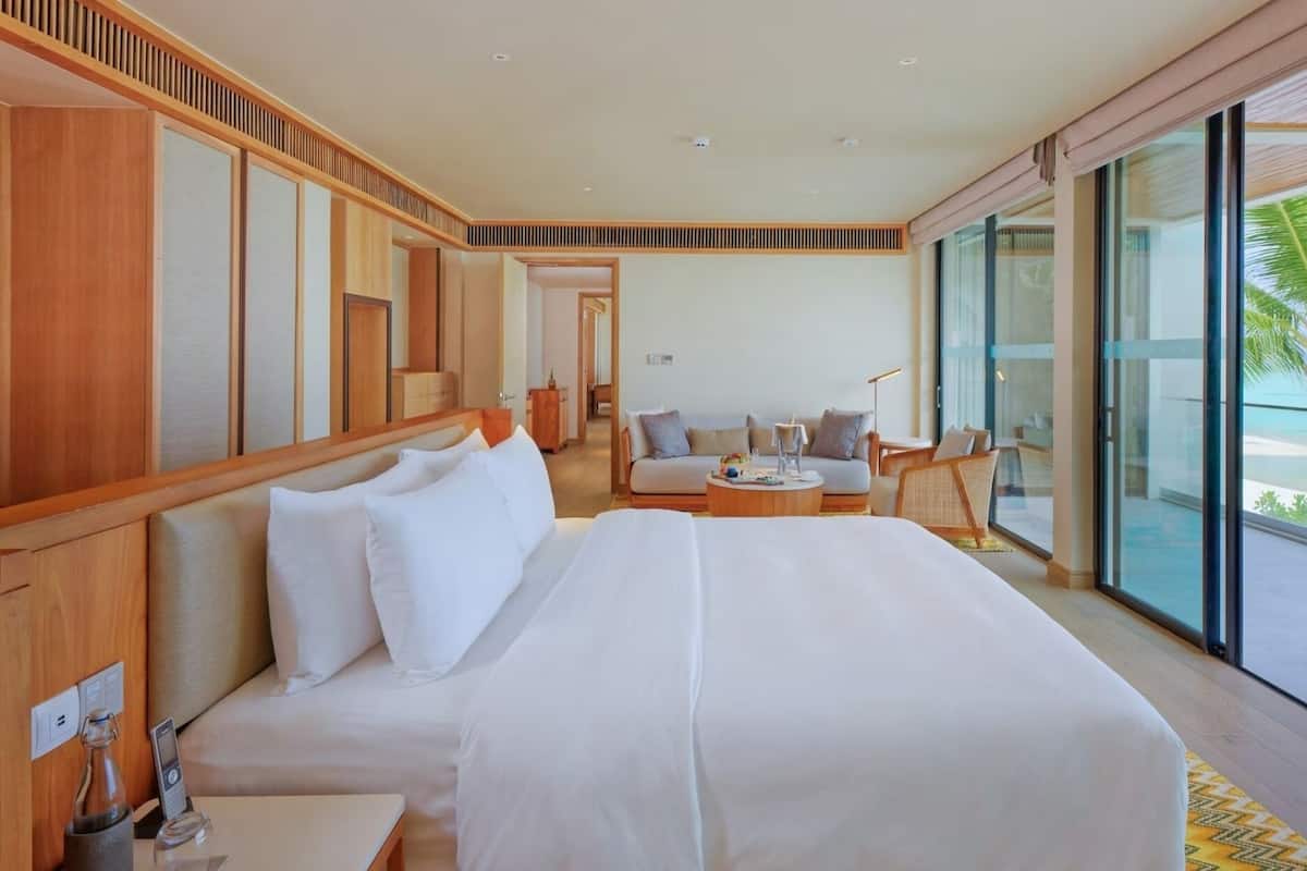 Une chambre d’hôtel avec un grand lit, un canapé, une table basse et une vue sur l’océan.