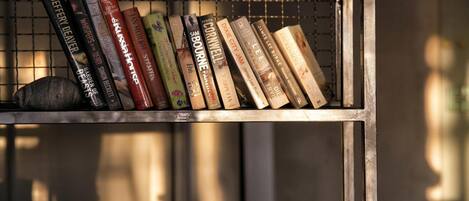 Una estantería de metal con libros y una roca.
