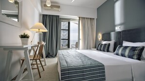 A hotel room with a bed, a desk, a chair, a potted plant, and a view of the outdoors. - Rigas Boutique Hotel (Kassandra)