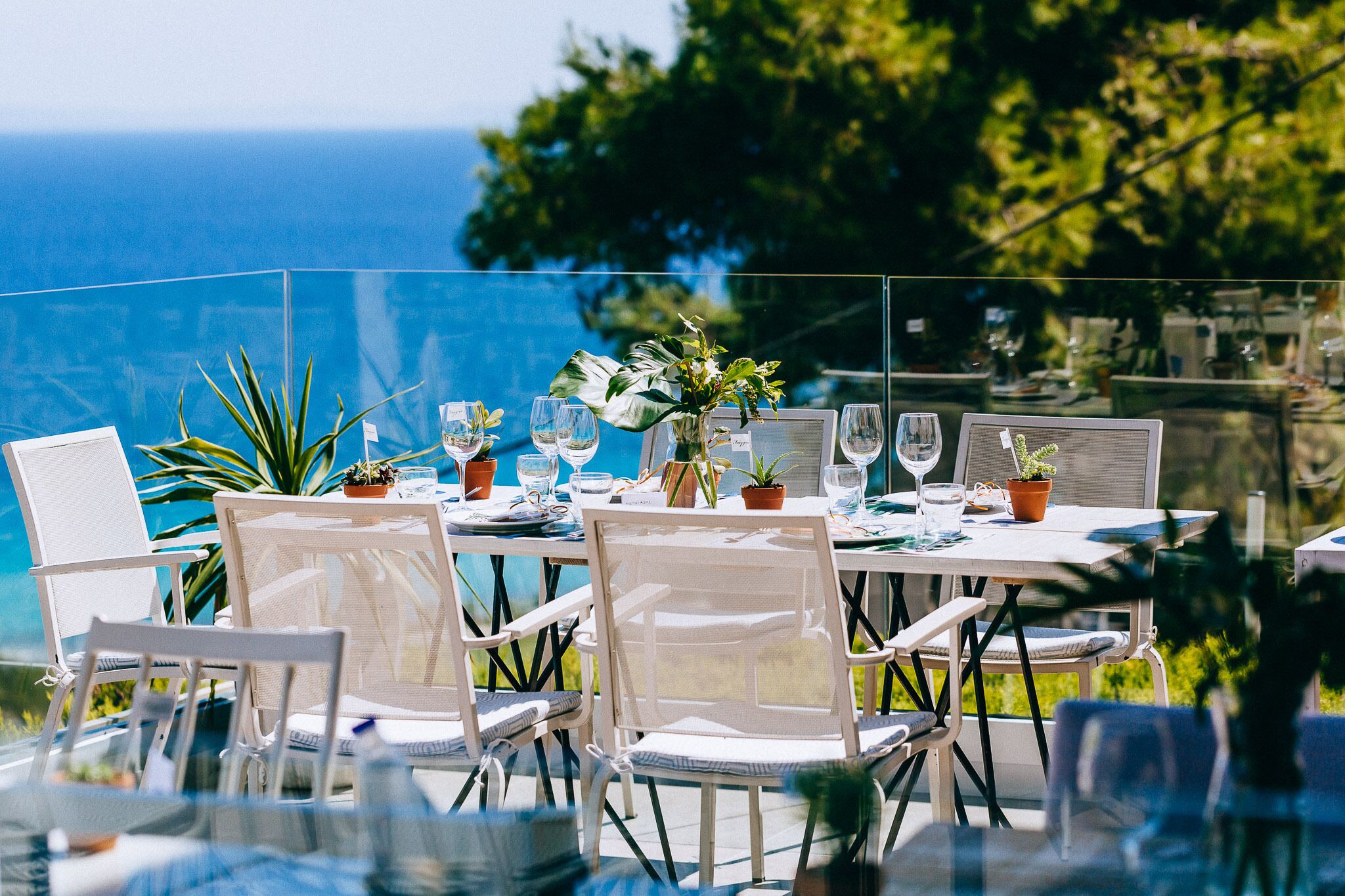 Un espace extérieur aménagé pour les repas, avec des tables pour deux personnes, des chaises et des plantes en pot.