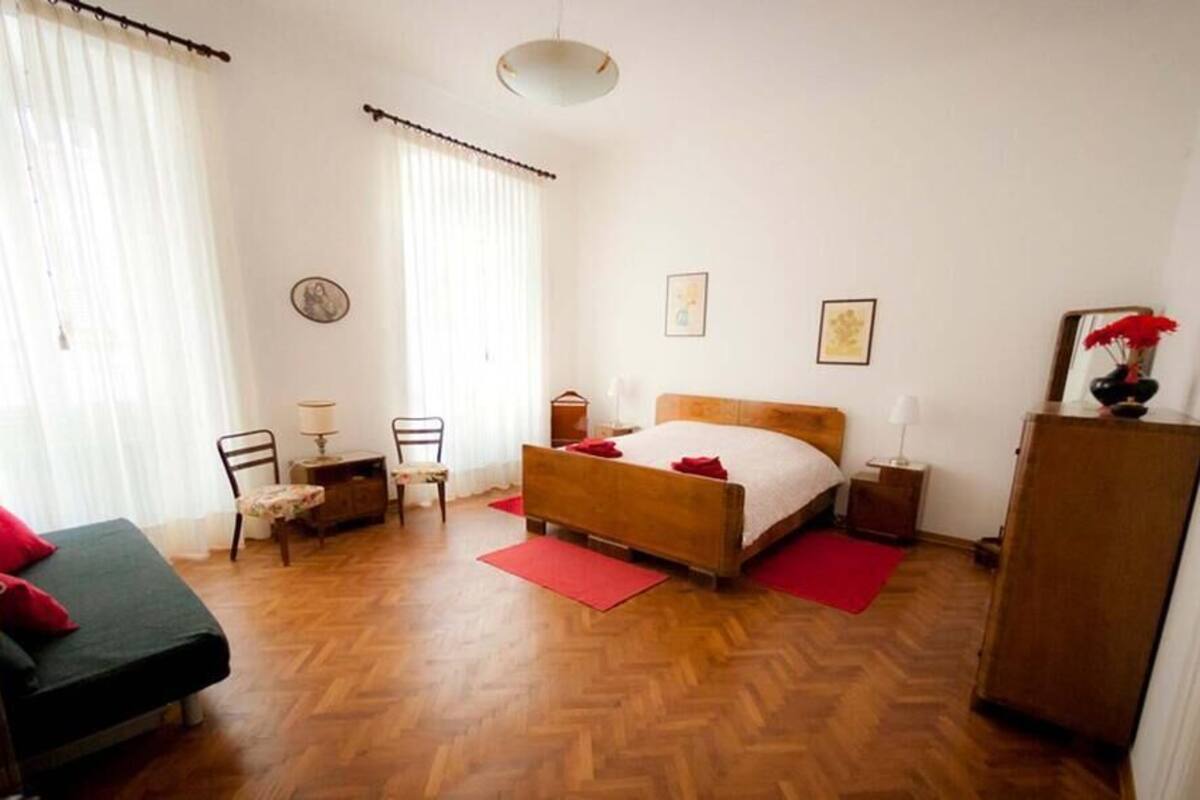 A bedroom with a bed, a desk, a chair, a wardrobe, and a window with curtains.