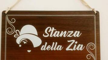 Une enseigne en bois portant l’inscription « Stanza della Zia » et ornée d’un chapeau décoratif.