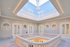 A grand interior with a central open space, ornate white railings, and a skylight. - Tandem Veedor De Galeras Suites (Cádiz)