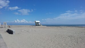 A beach with a lifeguard tower and a white structure with a curved roof. - Spacious 2 bed Appartment full air con, Sun terrace,stunning views, Pools (Fitou)