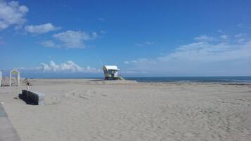 A beach with a lifeguard tower and a white structure with a curved roof.
