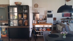 A modern kitchen with a wooden island, a black cabinet with glass doors, and a dining area with a table and chairs. - Spacious 2 bed Appartment full air con, Sun terrace,stunning views, Pools (Fitou)