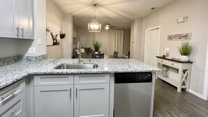 Eine moderne Küche mit Granit-Arbeitsplatten, einem Geschirrspüler und weißen Schränken.